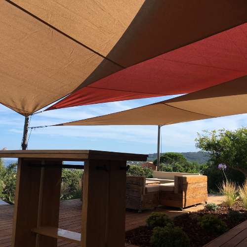 Voiles d'ombrage ajourées rouges et sables superposées pour terrasse de professionnels