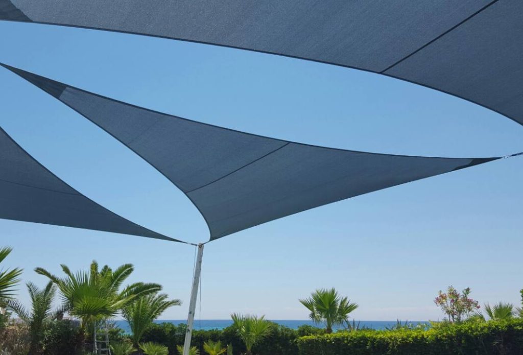 Voiles ombrage triangles bleu marine sur poteau bois sur une plage