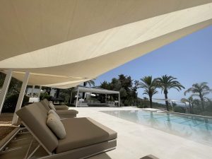 Voiles d'ombrage ajourées au bord d'une terrasse avec piscine