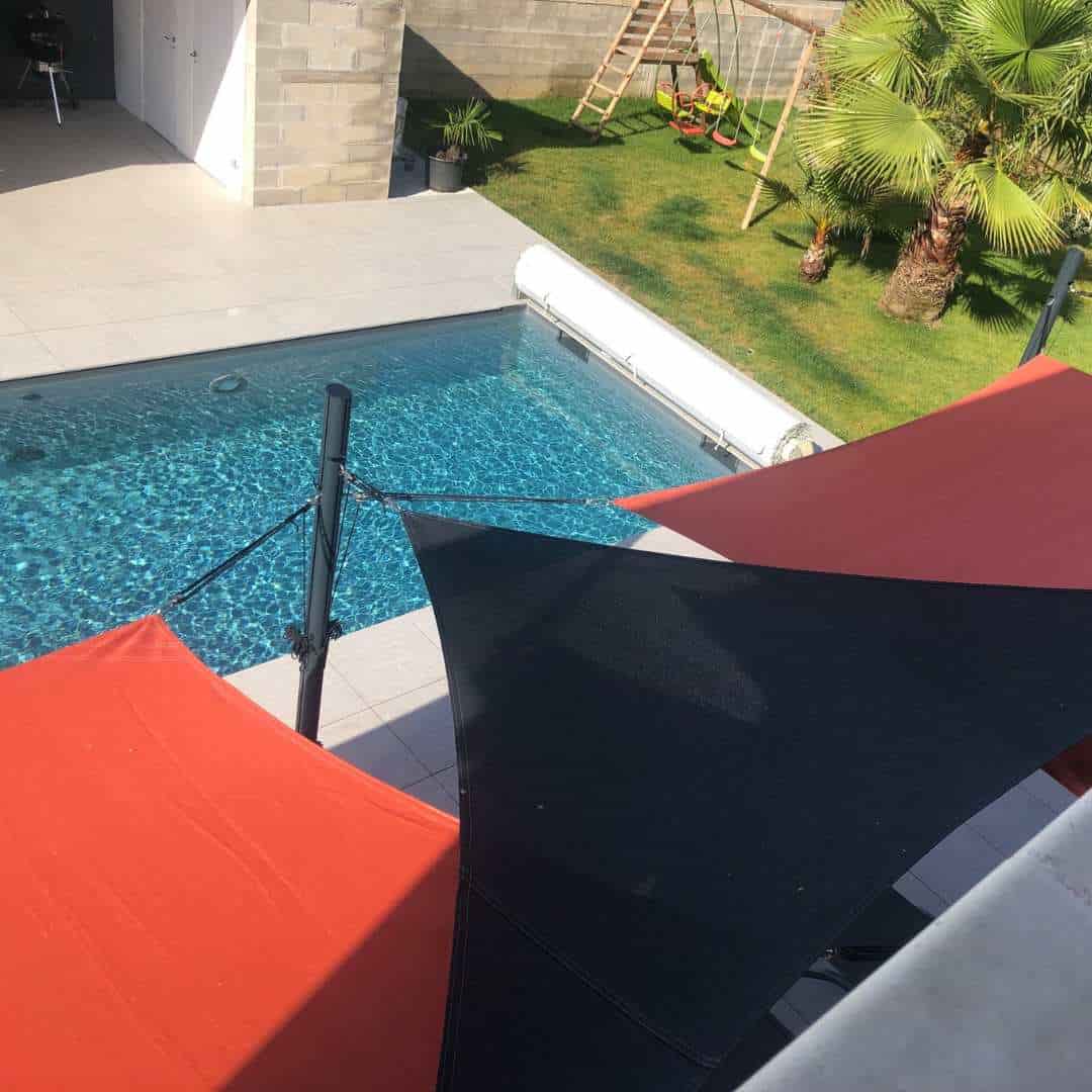 Toiles de terrasse installées sur des mats de voile ombrage au bord d'une piscine
