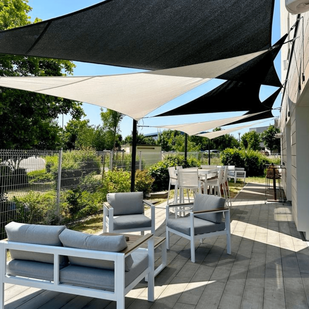 Toiles solaires triangulaires ajourées noires et naturelles pour terrasse d’hôtel